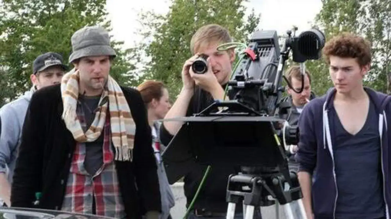 Junge Leute beim Filmstudium: Ein Kameramann blickt durch die Linse, während andere aufmerksam zusehen.
