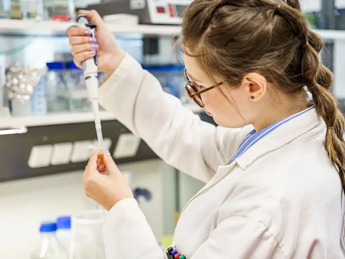 Studentin im Labor, die mit einer Pipette arbeitet. Ob an der uni oder Hochschule, hier wird geforscht.