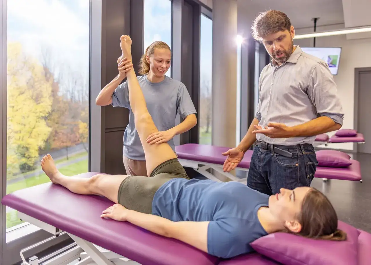 Ein Mann und eine Frau üben eine Beinübung im Rahmen ihres Studiums der Therapiewissenschaften.