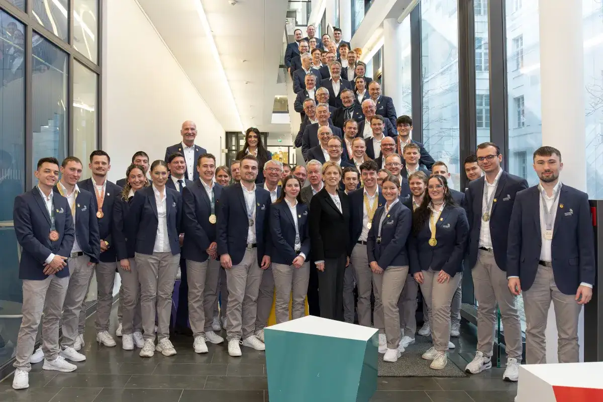 Eine große Gruppe von Menschen in Anzügen und Medaillen, die für Jobs mit Menschen stehen, posiert für ein Gruppenfoto auf einer Treppe.