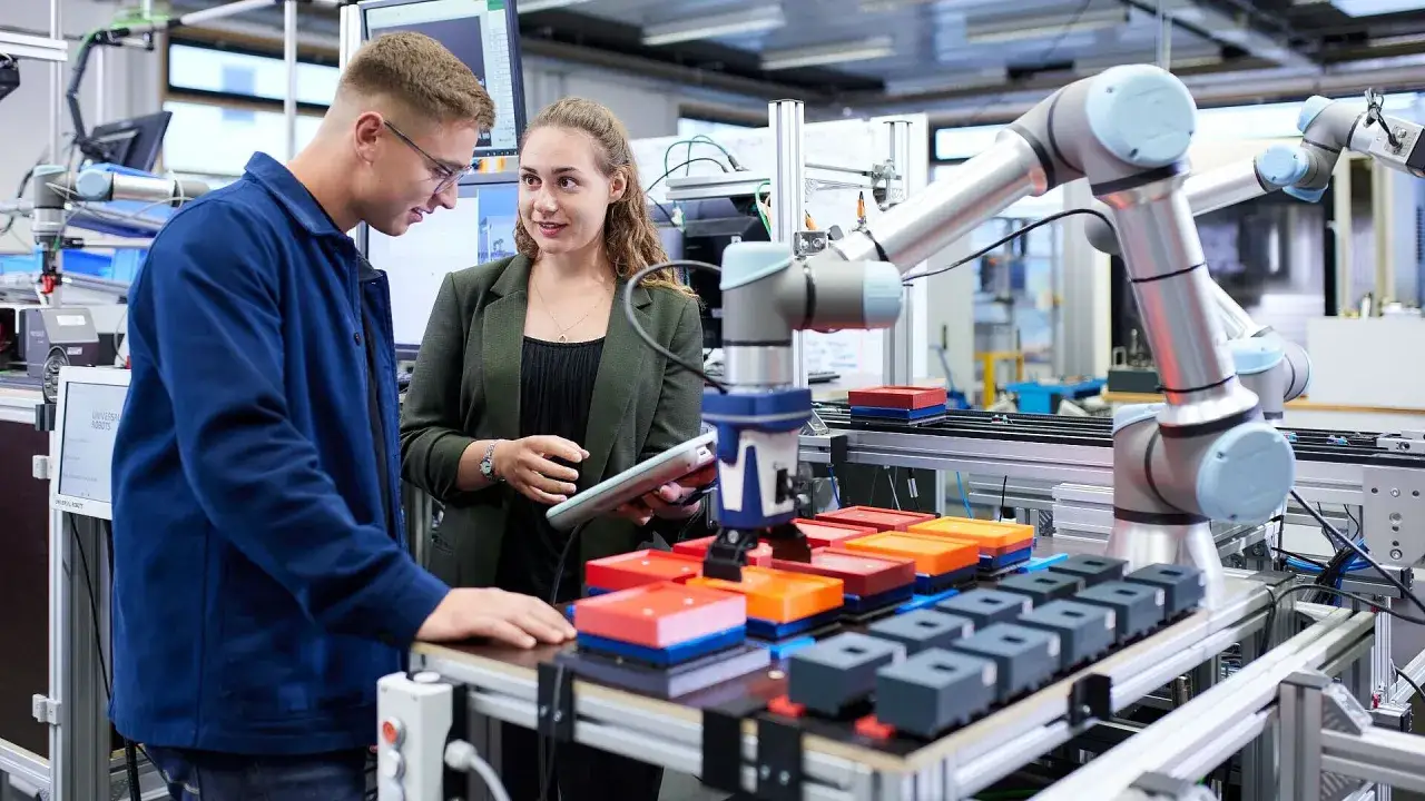 Zwei Ingenieure besprechen die Programmierung eines Roboterarms. Maschinenbau ist schwer, aber mit der richtigen Technologie machbar.