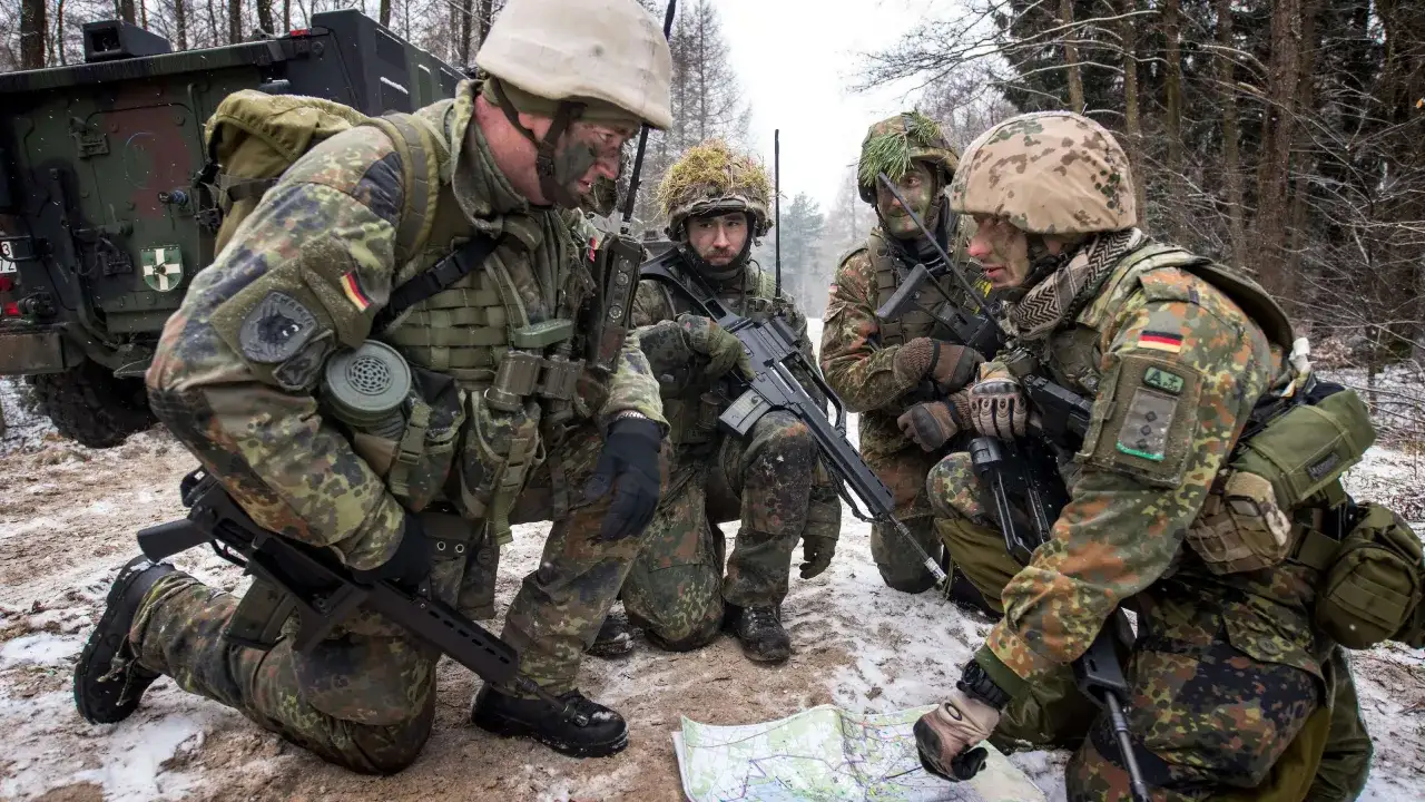 Vier Soldaten der Bundeswehr besprechen eine Karte im verschneiten Wald.