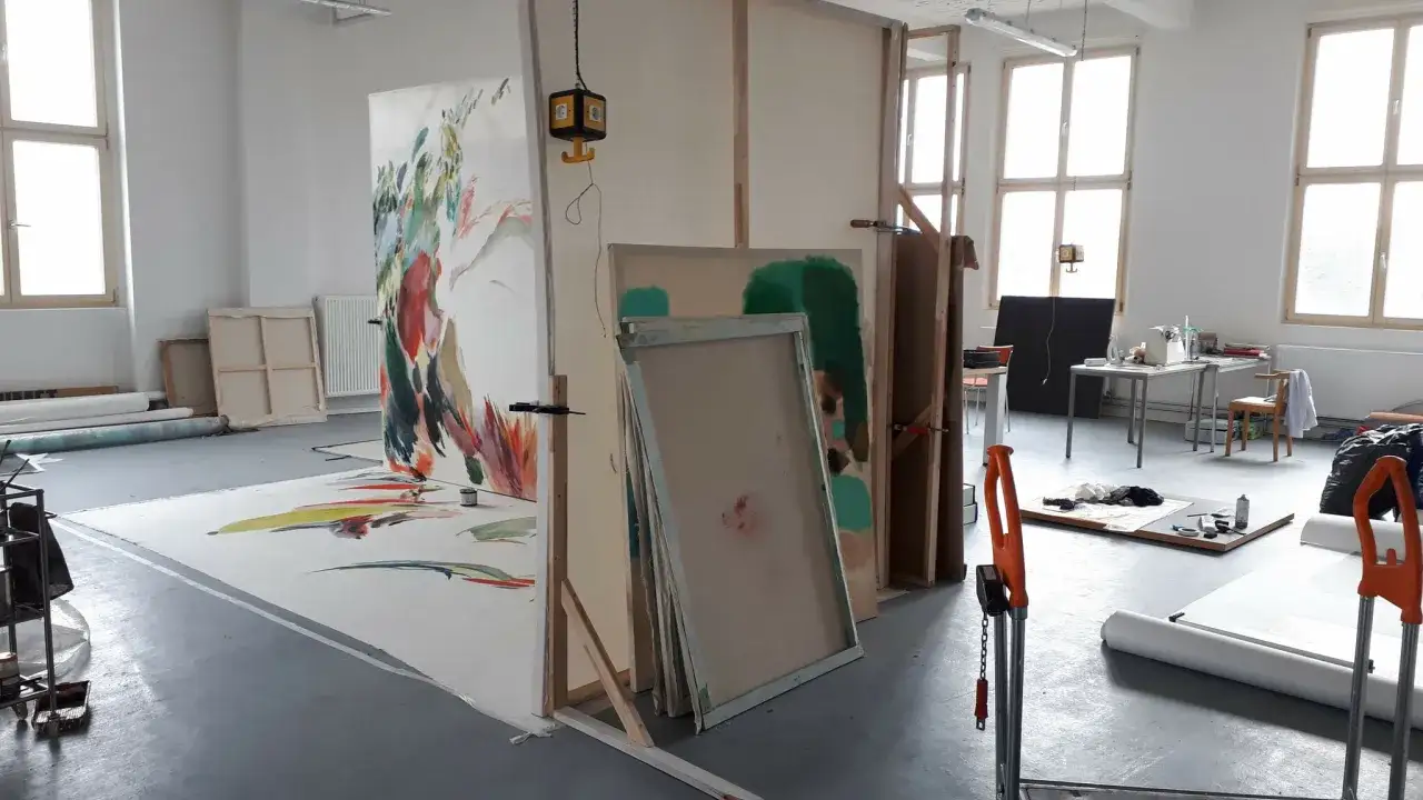 Künstleratelier in einer Berlin School of Arts mit großen Leinwänden, Staffeleien und Malutensilien.
