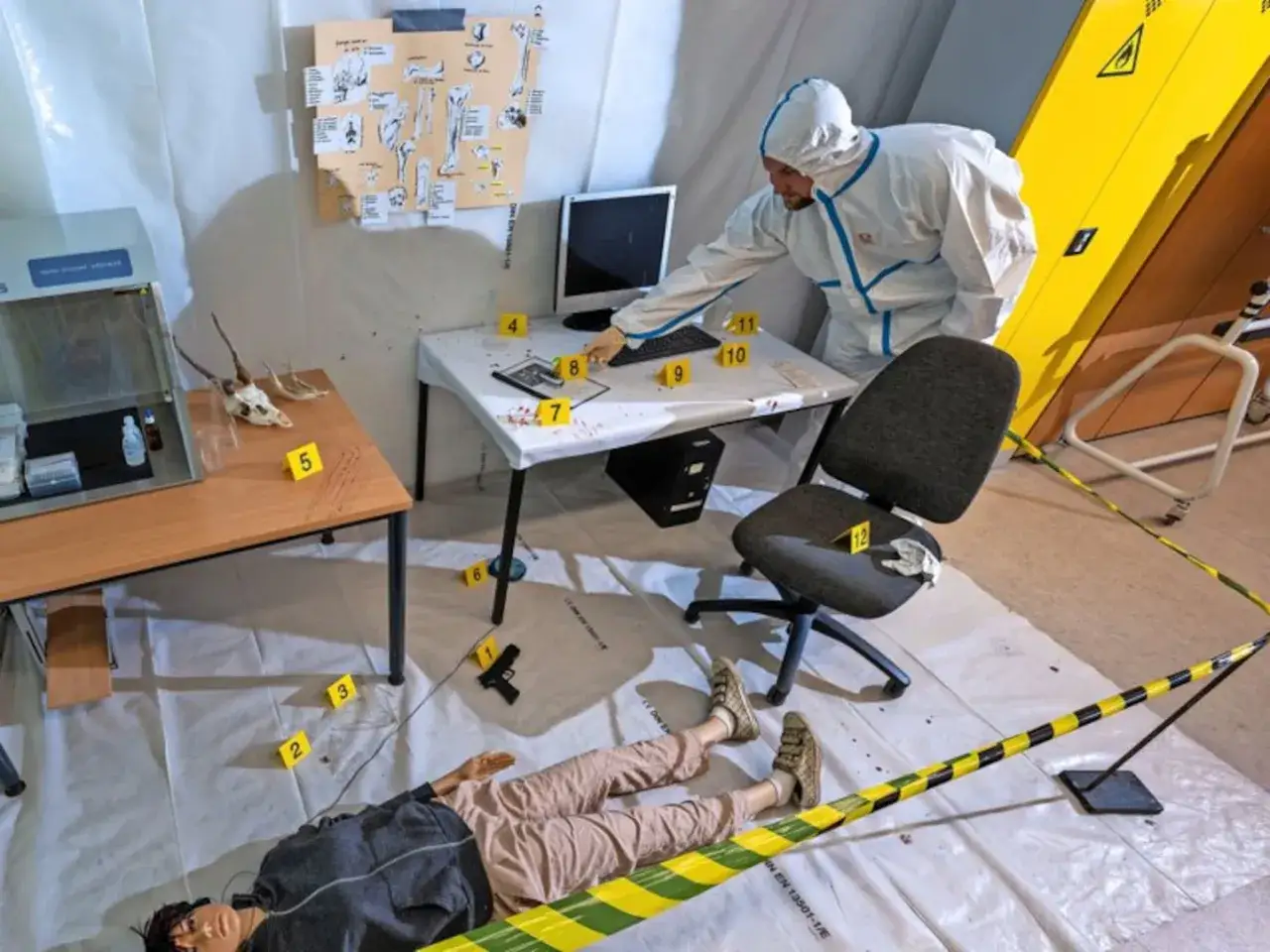 Szene eines Tatorts, wie er im digitale forensik studium analysiert wird. Ein Ermittler in Schutzanzug untersucht Beweismittel.