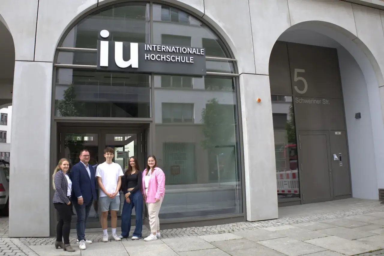 Fünf Personen stehen vor dem Gebäude der IU Internationale Hochschule in Leipzig.
