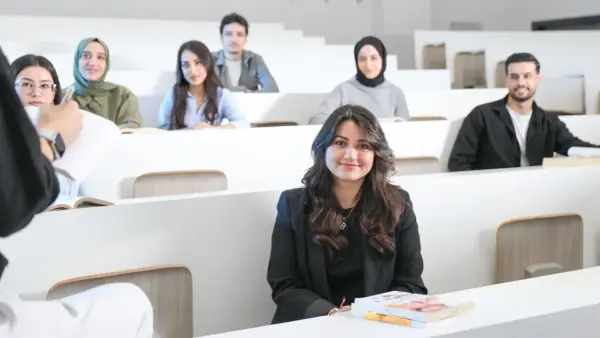 Junge Frau im Anzug in einem Hörsaal, umgeben von Kommilitonen. Sie lernt, um **Anwalt zu werden ohne Abitur**.